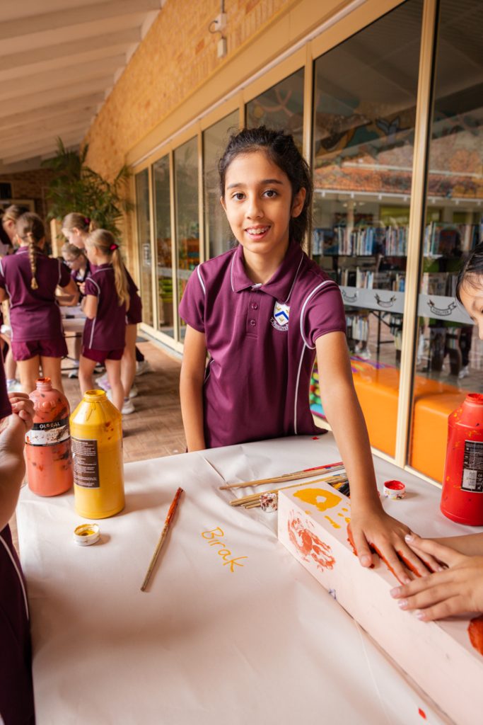 A Year 4 student placing a handprint on a wooden post