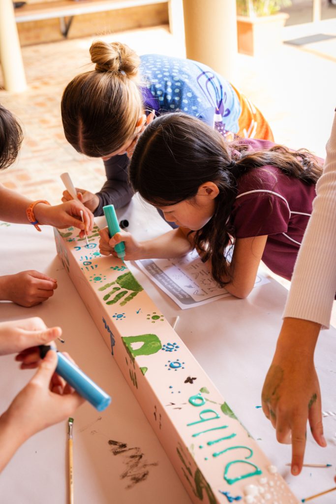 Senior School Indigenous students leading our Year 4s in painting wooden posts in traditional Indigenous art style.