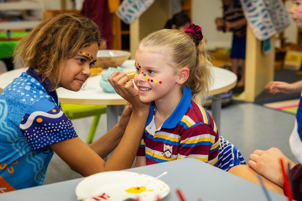 A Junior School student delighted to be having her face painted by one of the older students