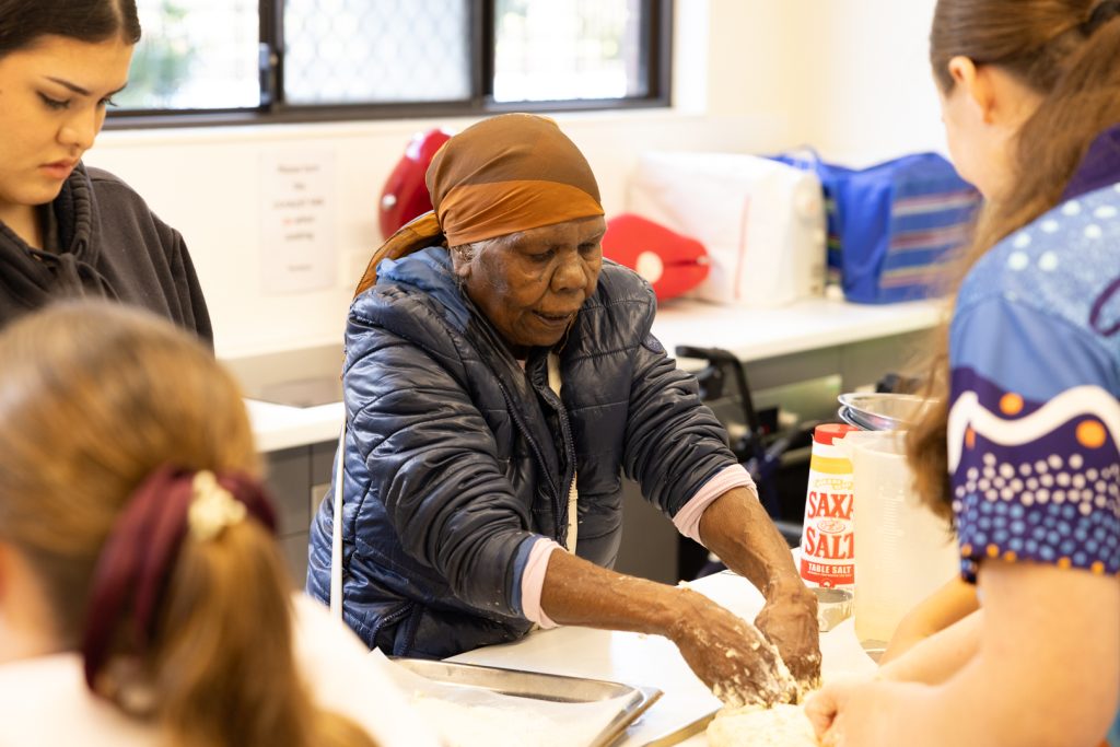 Jaja Valerie, the grandmother of one of our Year 8 students, leading the girls in a damper-making session.