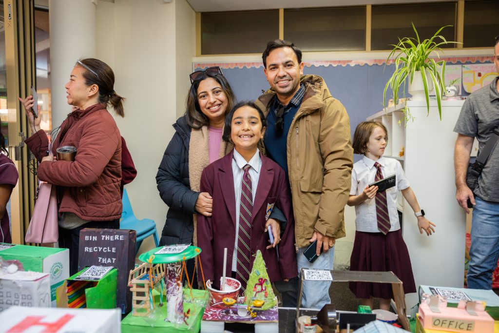 A student with her parents smiling proudly in front of Smagstown model