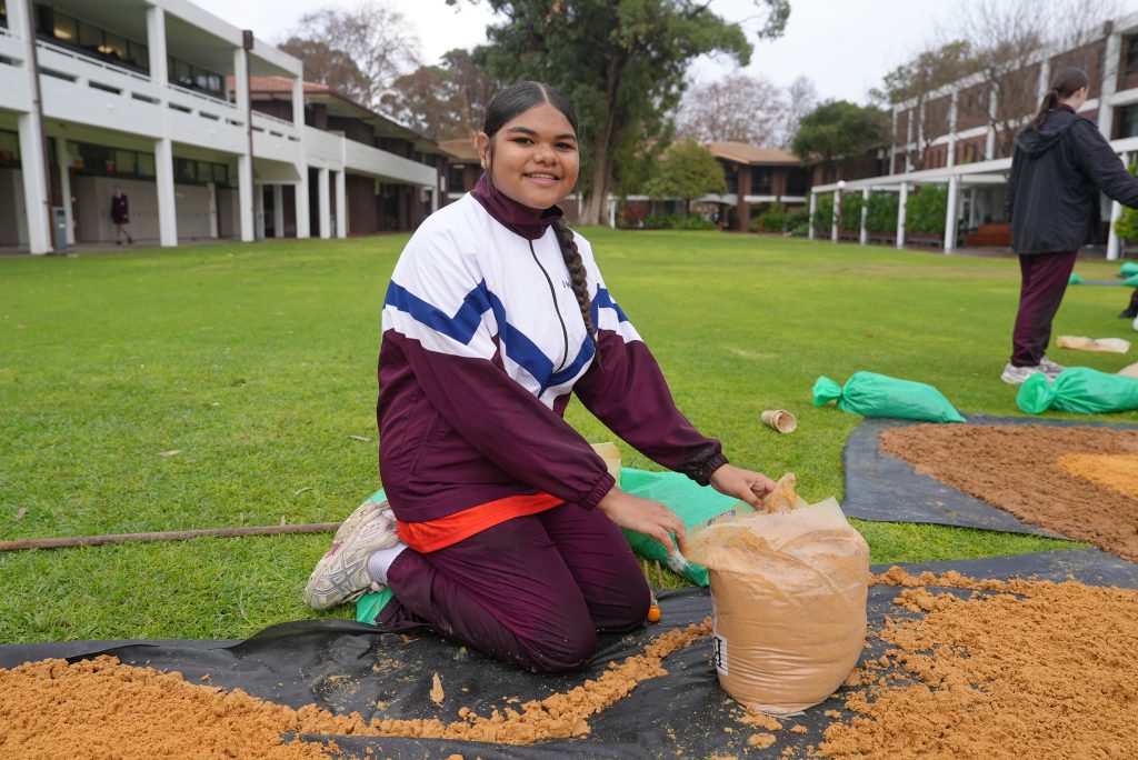 The girls working in the wind and rain to create this year's sand mural