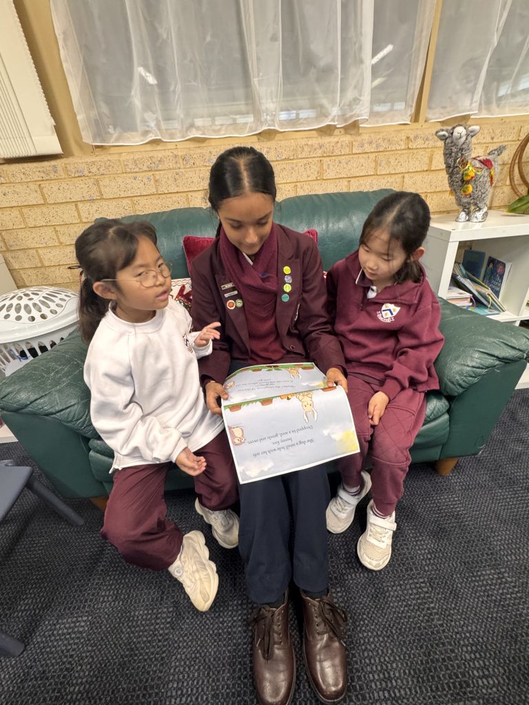 Year1 students listening intently while a Year 9 student reads their story