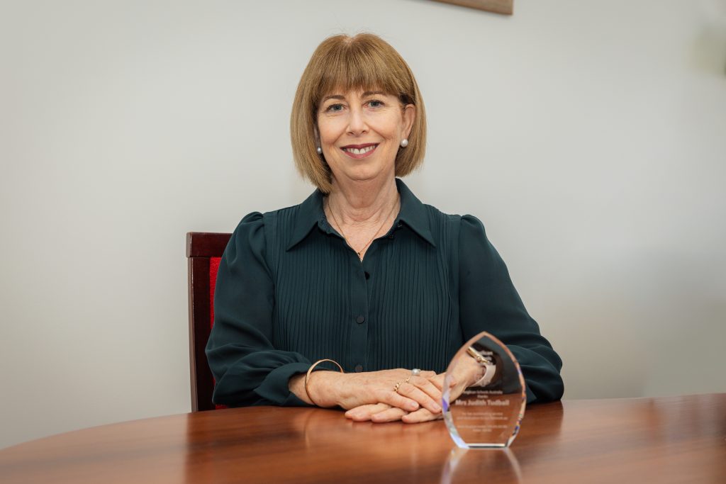 Principal Mrs Judith Tudball posing for a photo with the award she received in honour of her 10 years of service on the ASA's Management Committee.
